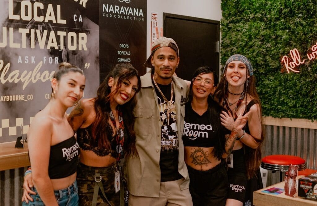 Smiling group standing in front of a Claybourne Co poster at Remedy Room.